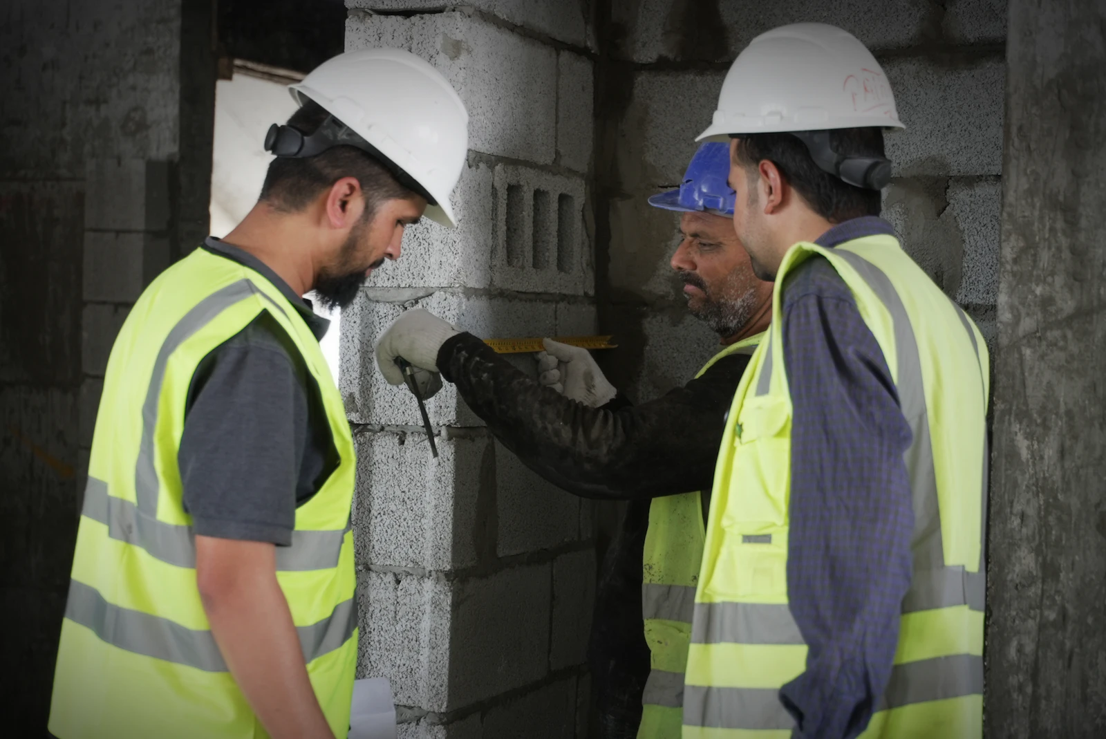 مشرفو موقع بناء بخوذات وسترات عاكسة يفحصون قياسات الجدار